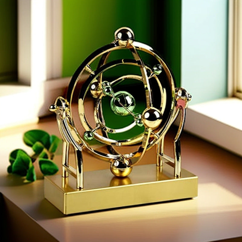 Gold and black spherical mechanical model on a reflective surface with green leaves.