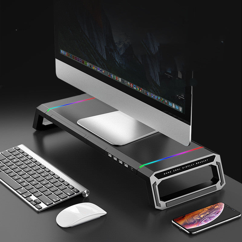 Monitor on a stand with keyboard, mouse, and smartphone on a dark surface