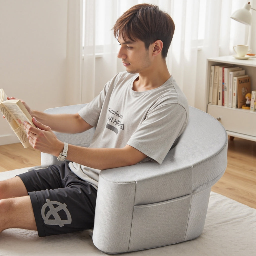 Person sitting on a bean bag chair reading a book in a bright room.