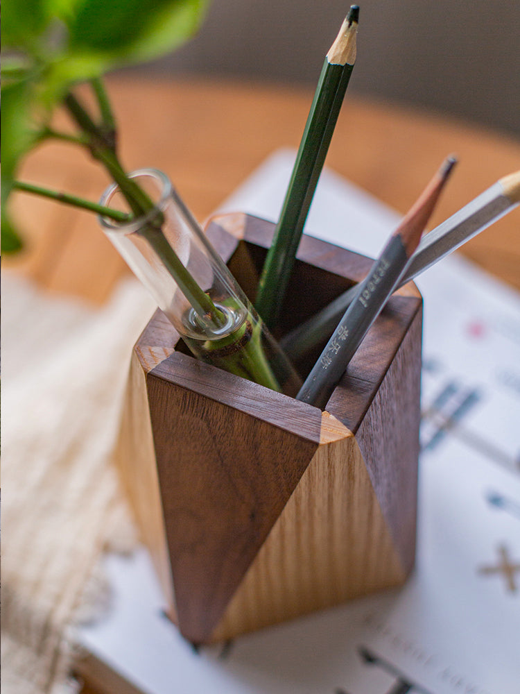 Wooden pencil holder with pencils and a plant on a table