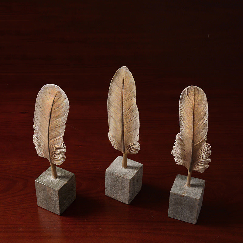 Three feather sculptures on concrete blocks against a dark background