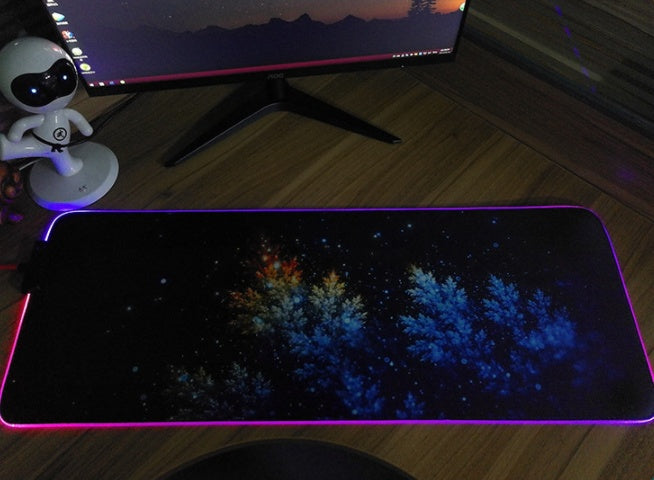 Large computer mouse pad with a starry night design on a desk.