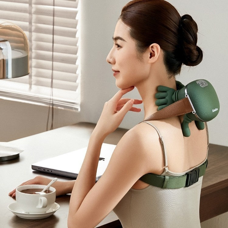Woman using a green massage device on her back in a home office setting.