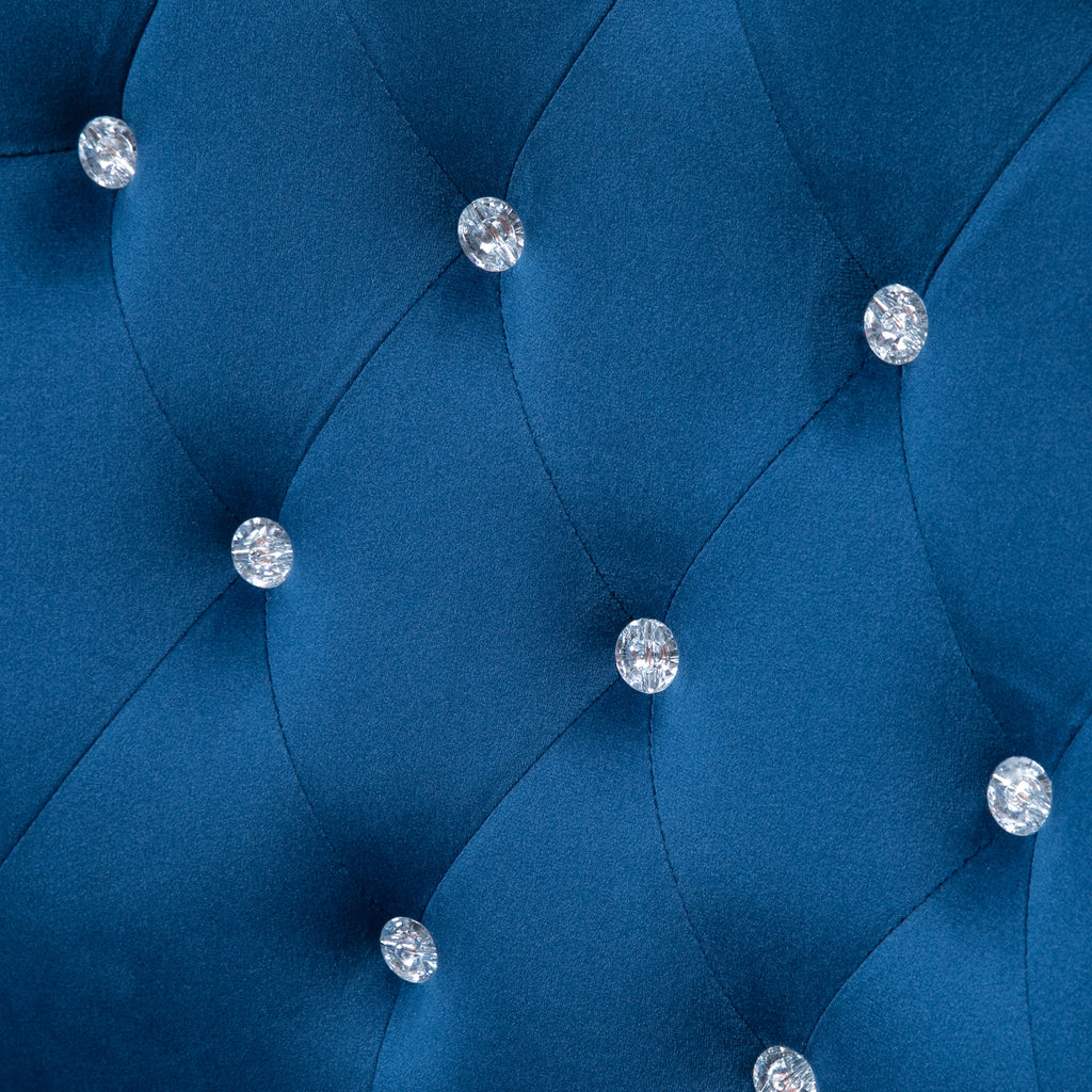 Close-up of a blue upholstered headboard with crystal buttons.