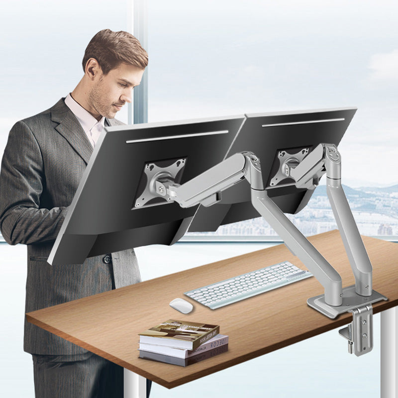 Man using a dual-monitor stand at a desk with a cityscape background