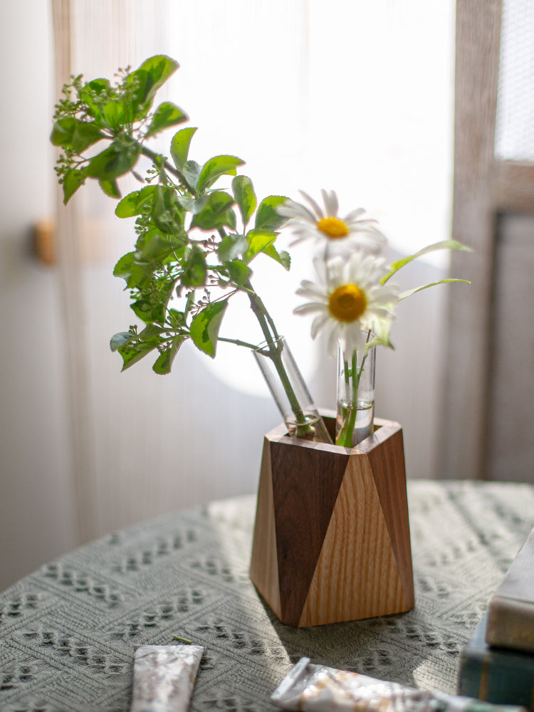 Wooden vase with greenery and a daisy on a textured surface