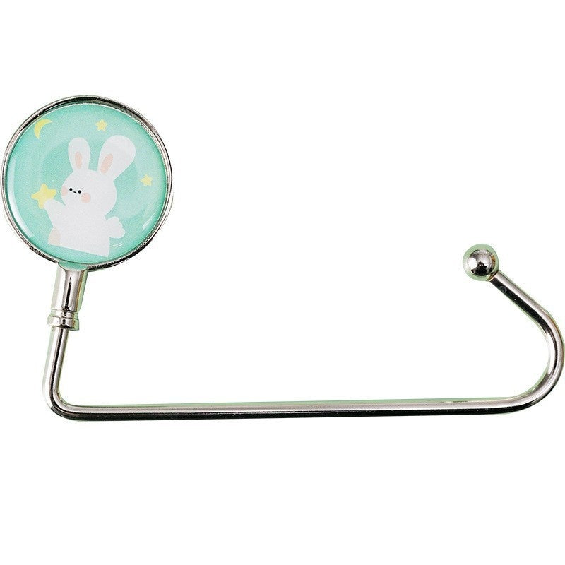 Metal bag hook with a cartoon bunny design on a light green background