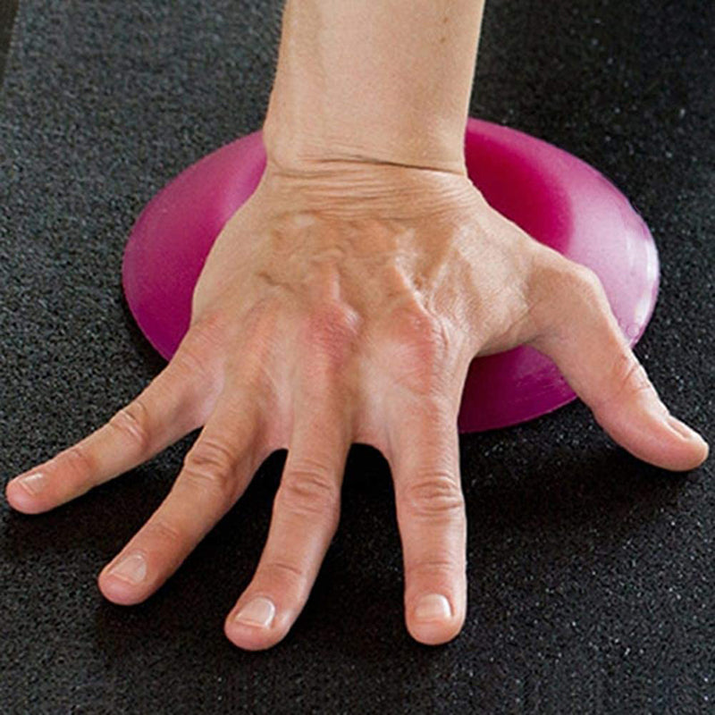 Hand on a pink exercise ball against a black background