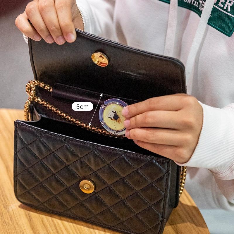 Black quilted handbag with gold accents held open by a person, showing interior space.