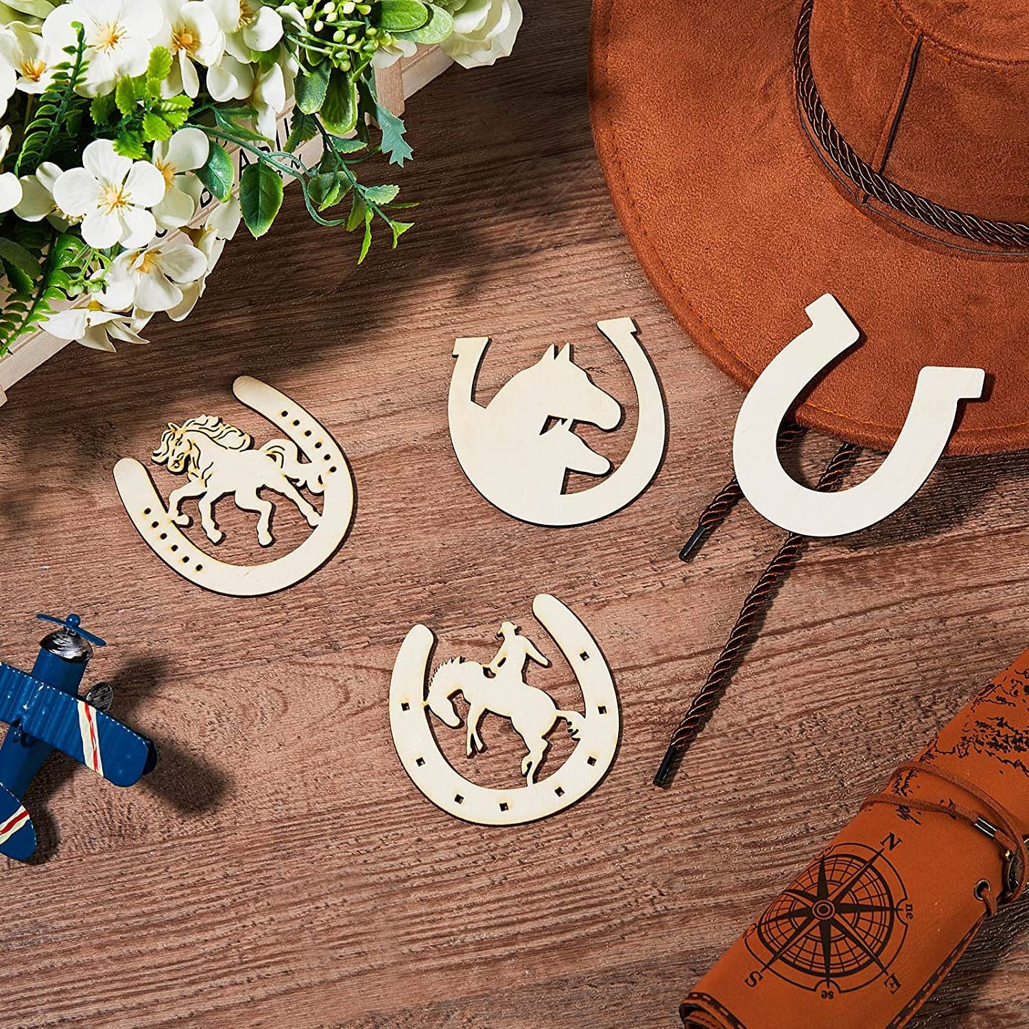 Wooden horse-shaped decorations on a wooden surface with a hat and flowers.