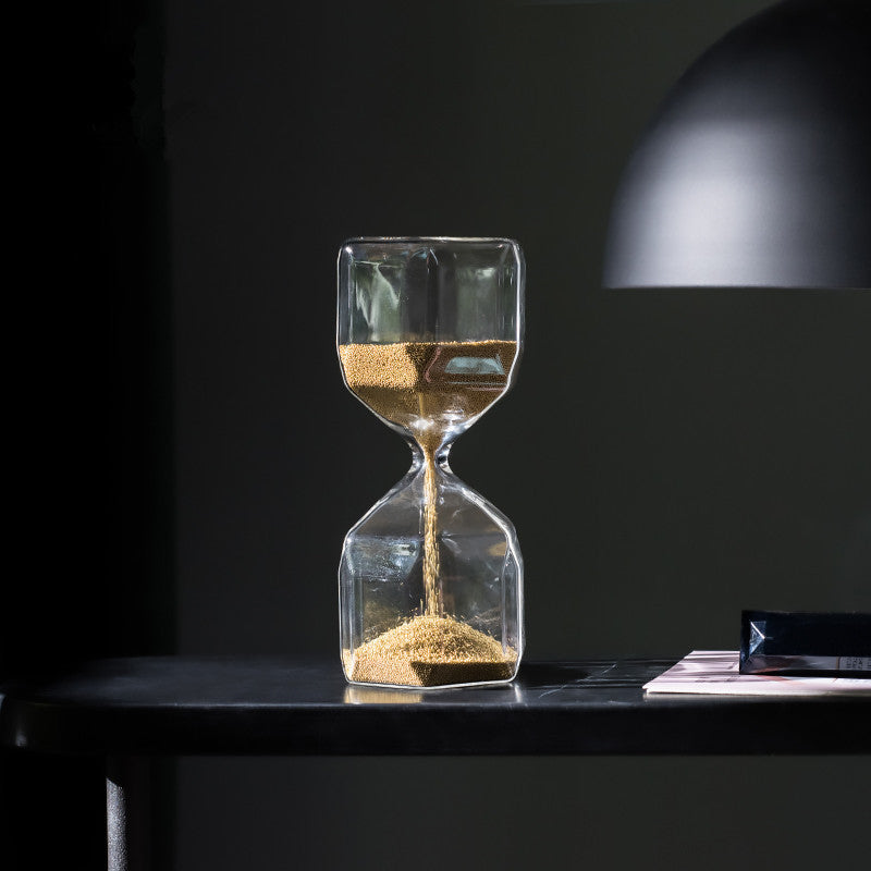 Hourglass with sand on a dark surface against a black background