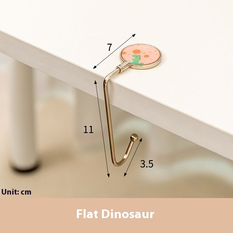 Measurement chart of a gold hook with a flat dinosaur design on a white surface.