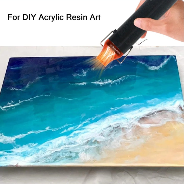 Hand using a resin gun to create an ocean-themed acrylic resin art piece.