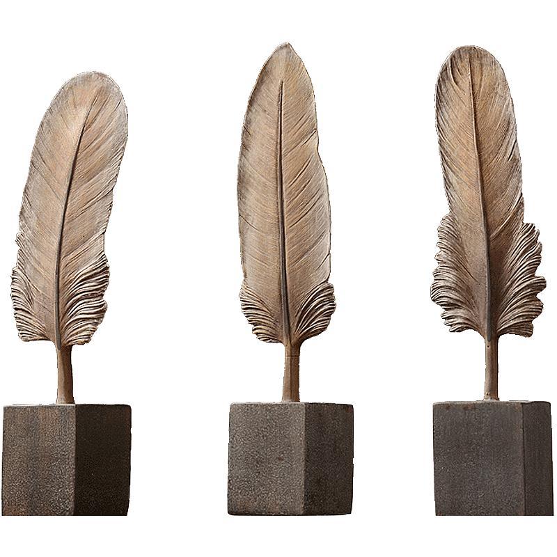 Three feather-shaped decorative items on wooden bases against a white background