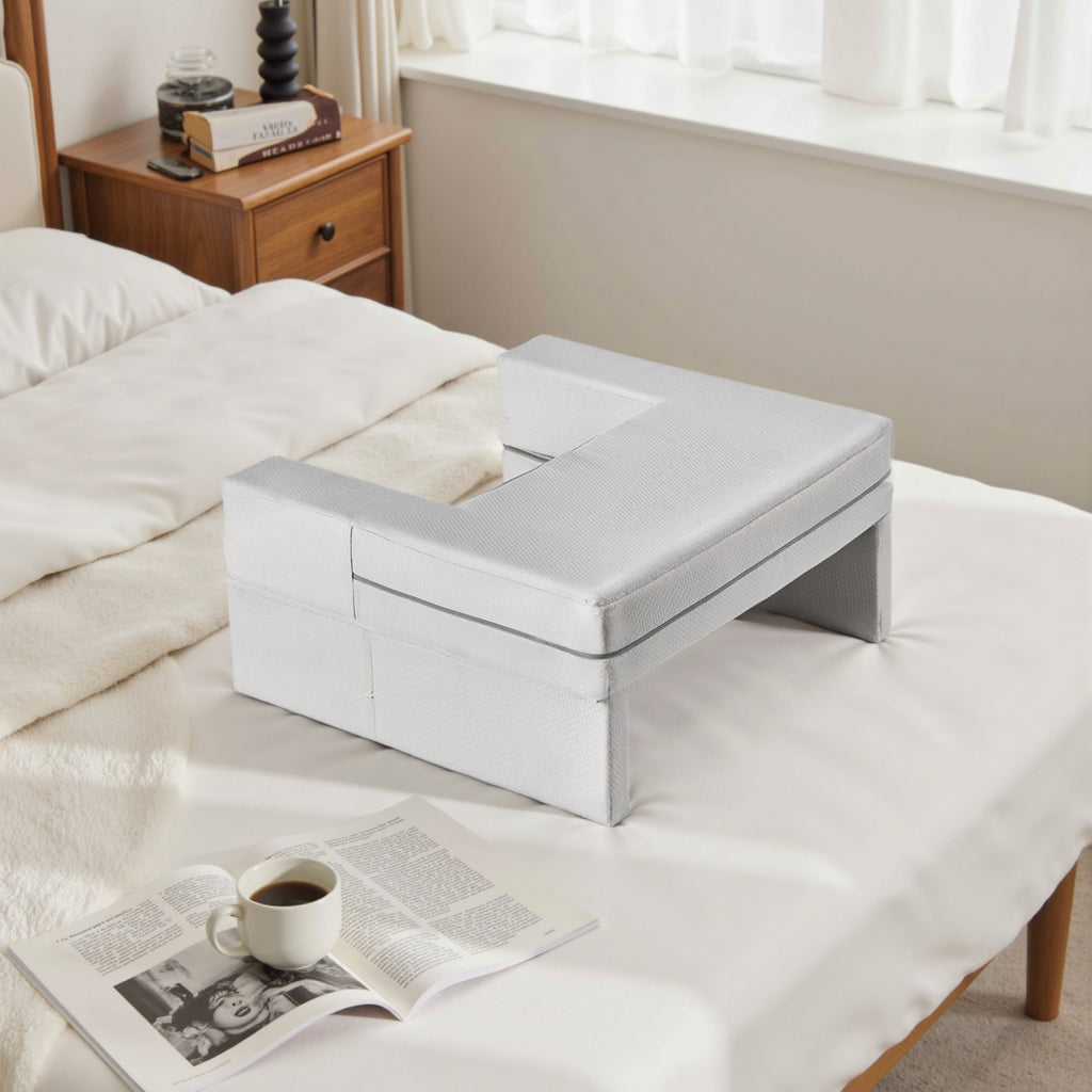 White ottoman with storage compartments on a bed in a bedroom setting.