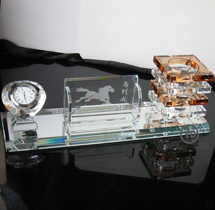 Crystal desk set with clock, card holder, and pen holder on a reflective surface.