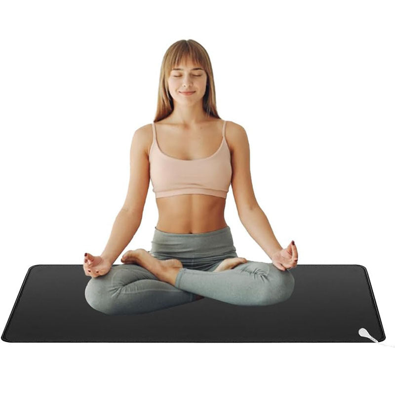 Woman practicing yoga on a black mat with a white background